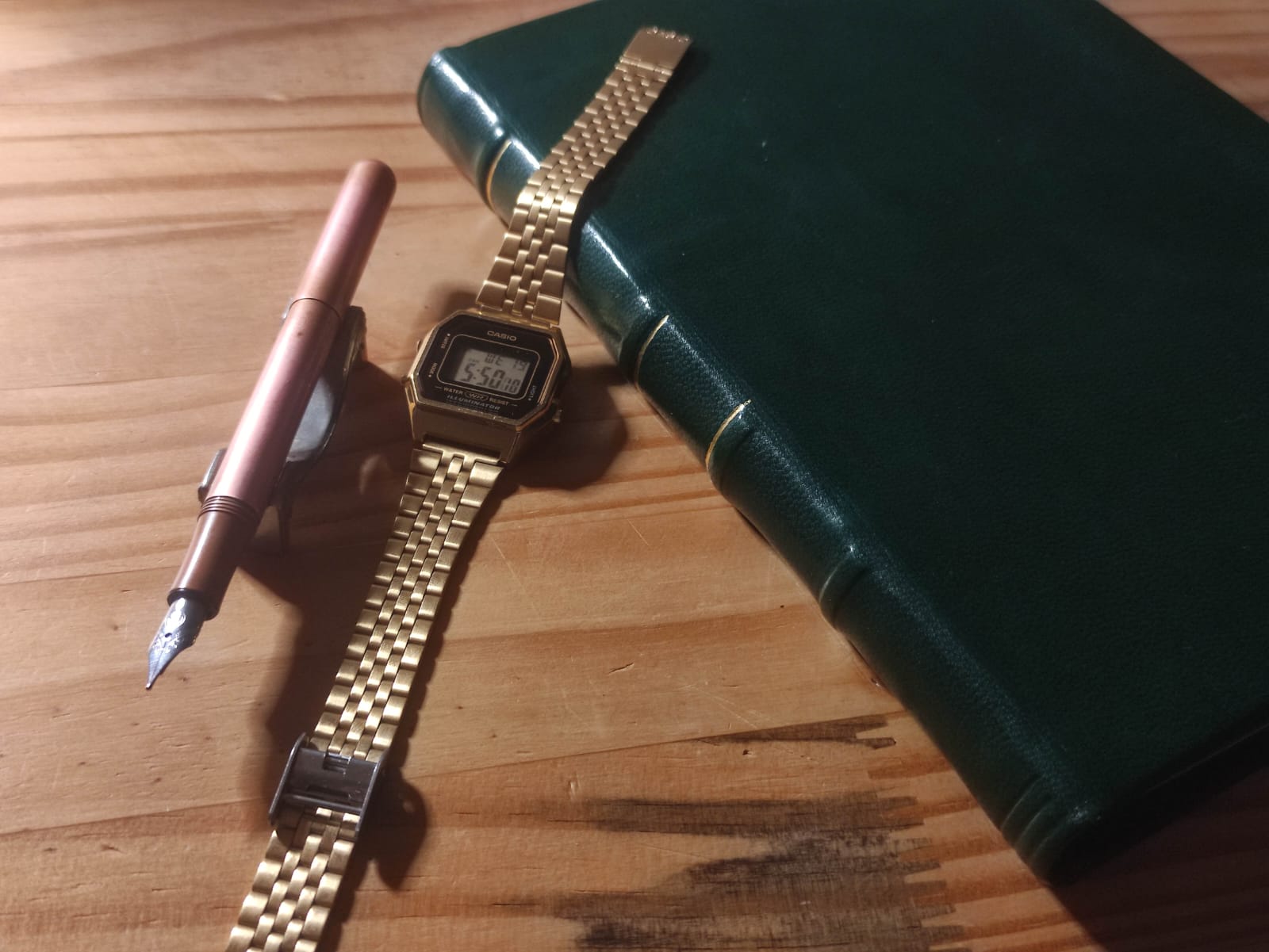 photographie de mon nouveau journal, un carnet A5 relié en cuir vert foncé et quelques lignes dorées sur le dos ; on voit aussi ma montre Casio dorée, et mon stylo plume petit et fin, en cuivre massif